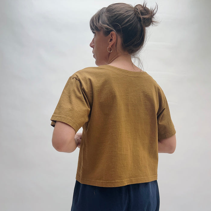 Person wearing a brown t-shirt against a plain background, viewed from the back