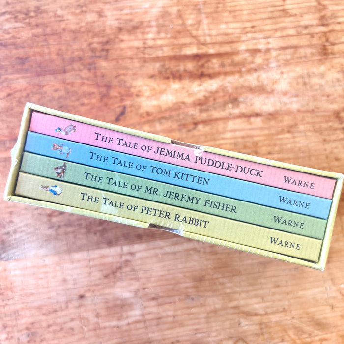 Set of children's books in a box with titles on a wooden surface