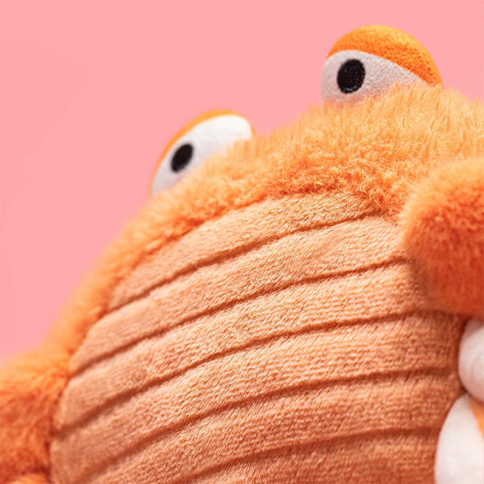 Close-up of a plush crab toy with a pink background