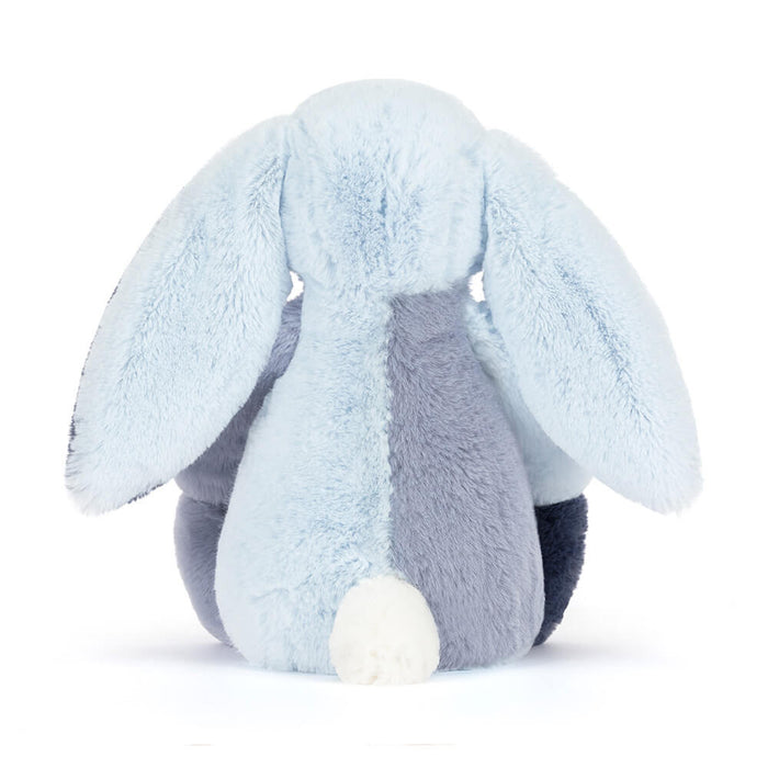 Plush toy rabbit with light blue and dark blue color scheme on a white background as seen from behind