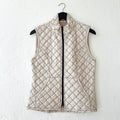Cream-colored quilted vest with a diamond pattern on a hanger against a white wall