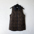 Patterned vest with black collar on a hanger against a white wall