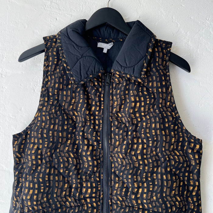 Black patterned vest on a hanger against a white wall