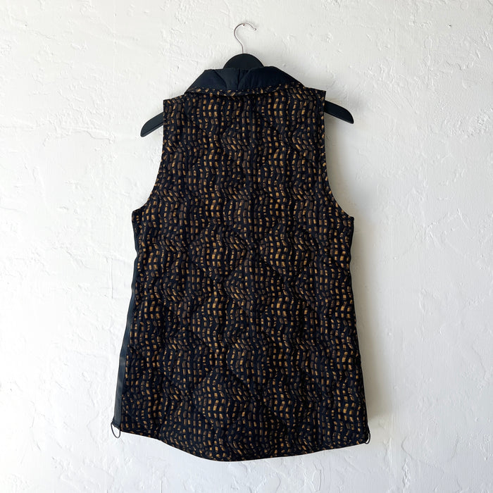 Black patterned vest on a hanger against a white wall