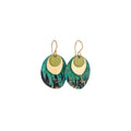 Pair of Sibilia Rock Earrings in Forest, featuring a small matte gold crescent-shaped disc layered over a large oval treated brass drop with a dramatic forest green, teal, black, and gold speckle oxide patina finish, on gold wire hooks, on a white background