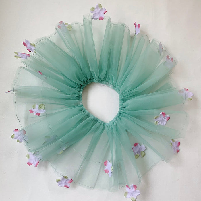 A sage green tutu with lavender colored flowers and an elastic waistband, displayed on a neutral background.