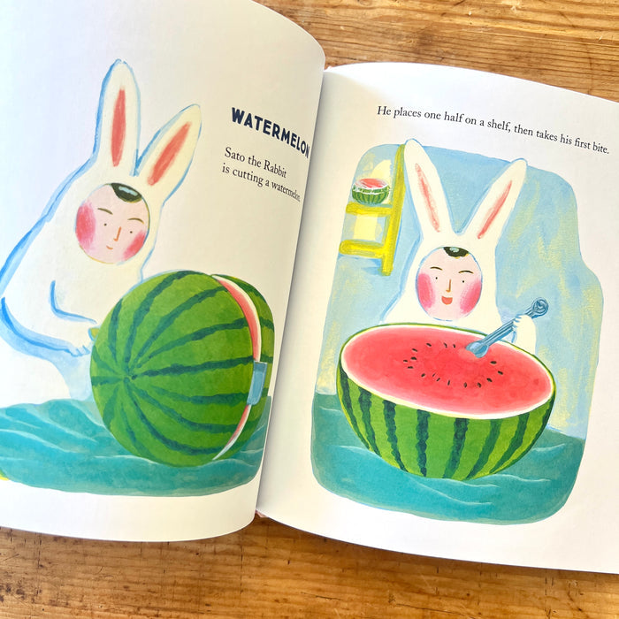 Open book showing illustrations of a rabbit character with watermelon slices on a wooden surface