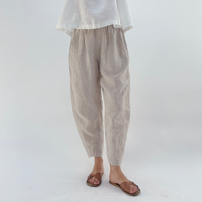 Person wearing beige linen pants and a white linen tank on a white background.