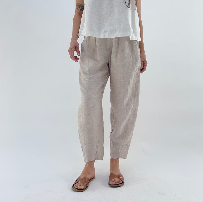 Person wearing beige linen pants and a white linen tank on a white background.
