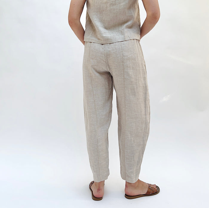 Person wearing beige linen pants and a matching linen tank on a white background as seen from behind.