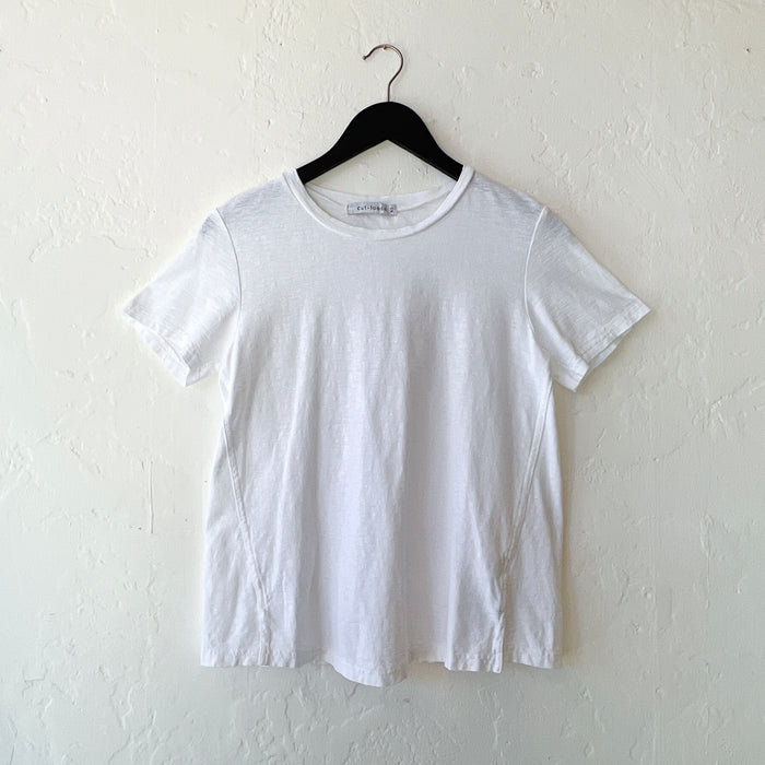 White t-shirt on a hanger against a white wall