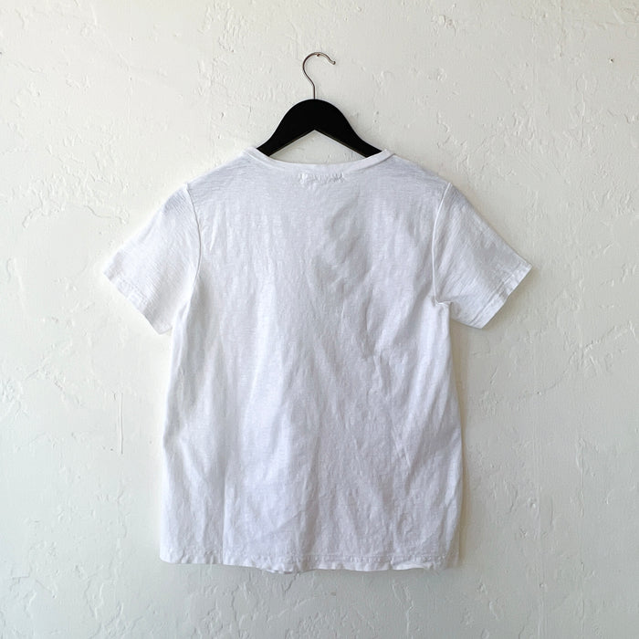 White t-shirt on a black hanger against a white wall