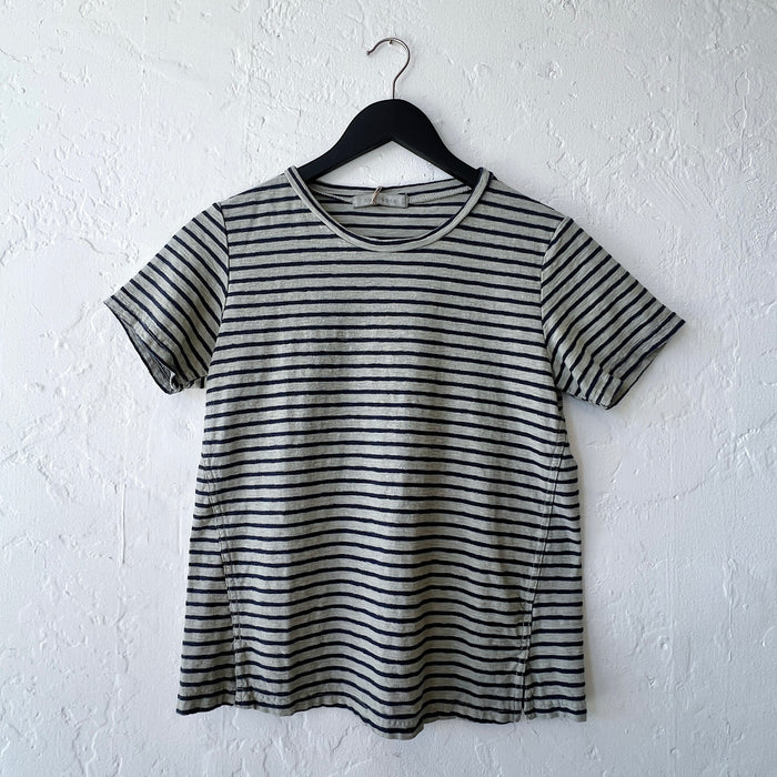 Green and black striped t-shirt on a hanger against a white wall