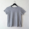 A striped navy and white short sleeve tee with slit hem, displayed on a hanger against a white wall.