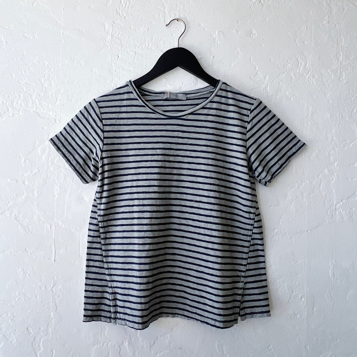Gray and black striped t-shirt on a hanger against a white wall