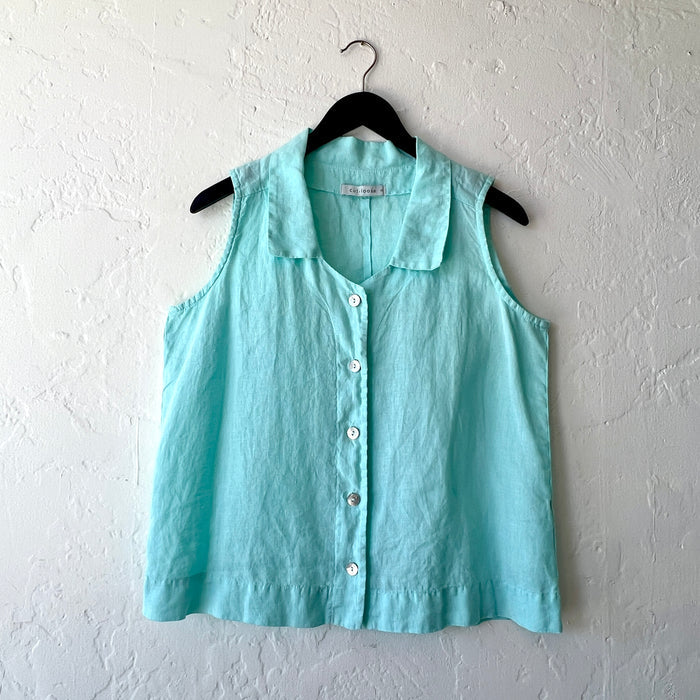Light blue sleeveless button-up shirt on a hanger against a white wall
