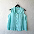 Light blue sleeveless button-up shirt on a hanger against a white wall