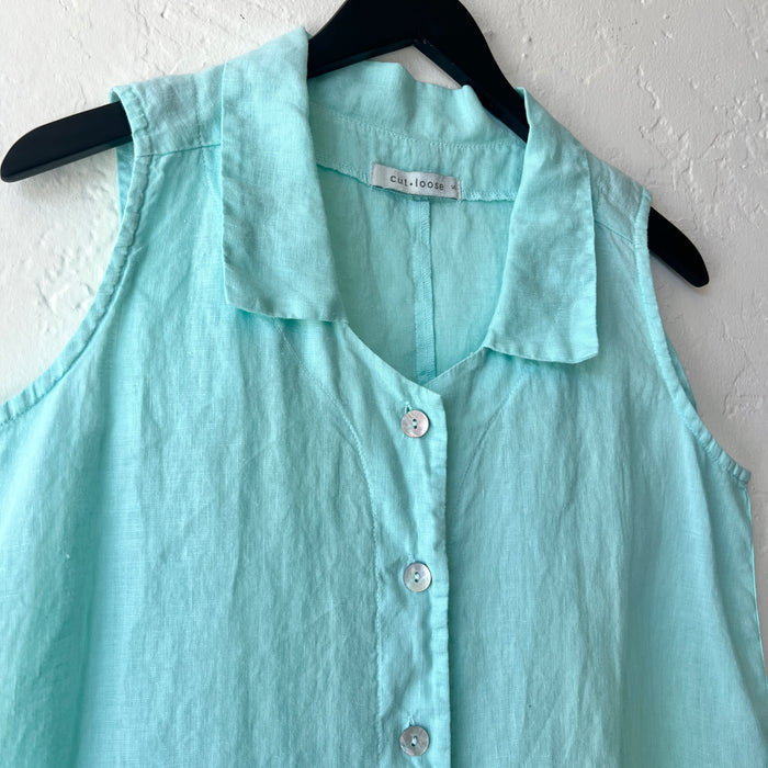 Light blue sleeveless shirt on a hanger against a white wall