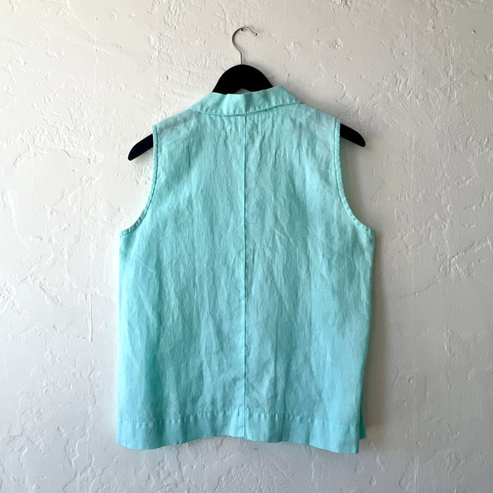 Light blue sleeveless shirt on a hanger against a white wall, viewed from behind.