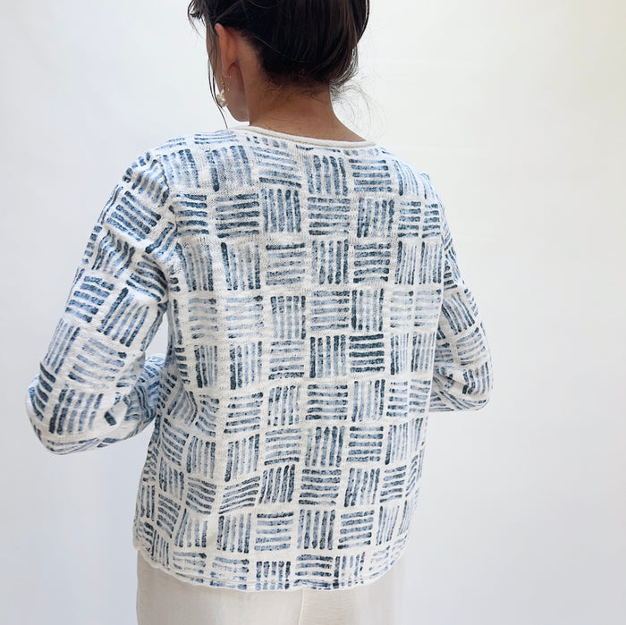 Back view of the Softly Stamped Cardigan in White showing the all-over navy brushstroke grid print on a white cotton knit