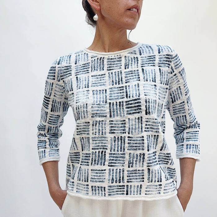 Front close-up of the Softly Stamped Pullover in White showing the round neckline and all-over navy brushstroke grid print on white cotton knit, with three-quarter sleeves
