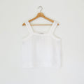 White tank top on a wooden hanger against a white background