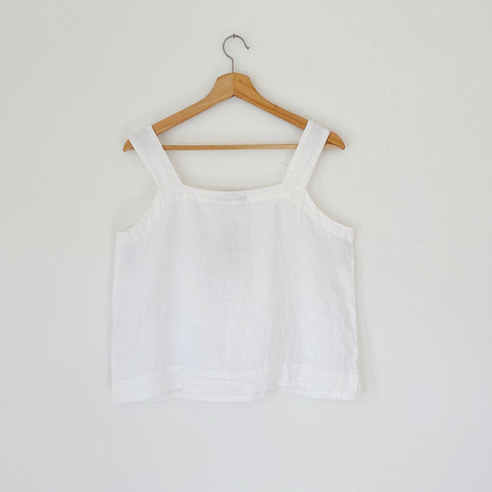 White tank top on a wooden hanger against a white background, viewed from the back