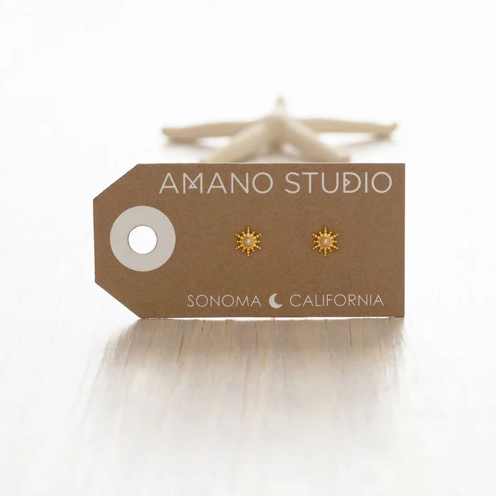 Gold sun-shaped earrings on a 'Amano Studio' branded card with a white background