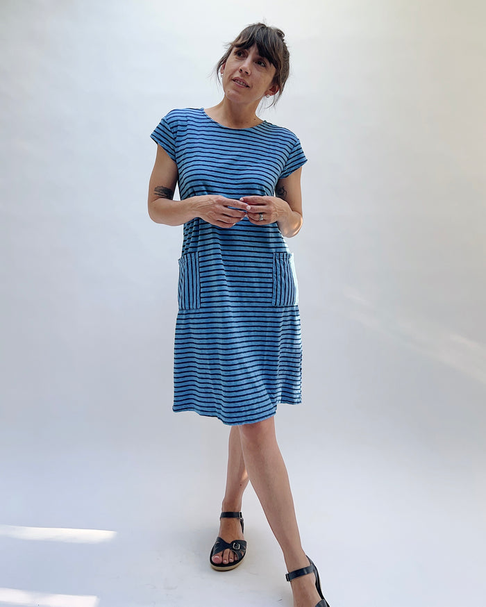 Woman wearing a dark-blue and light-blue striped dress on a white background