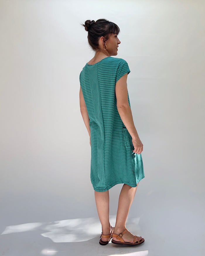 Woman wearing a green dress against a white background, viewed from the back
