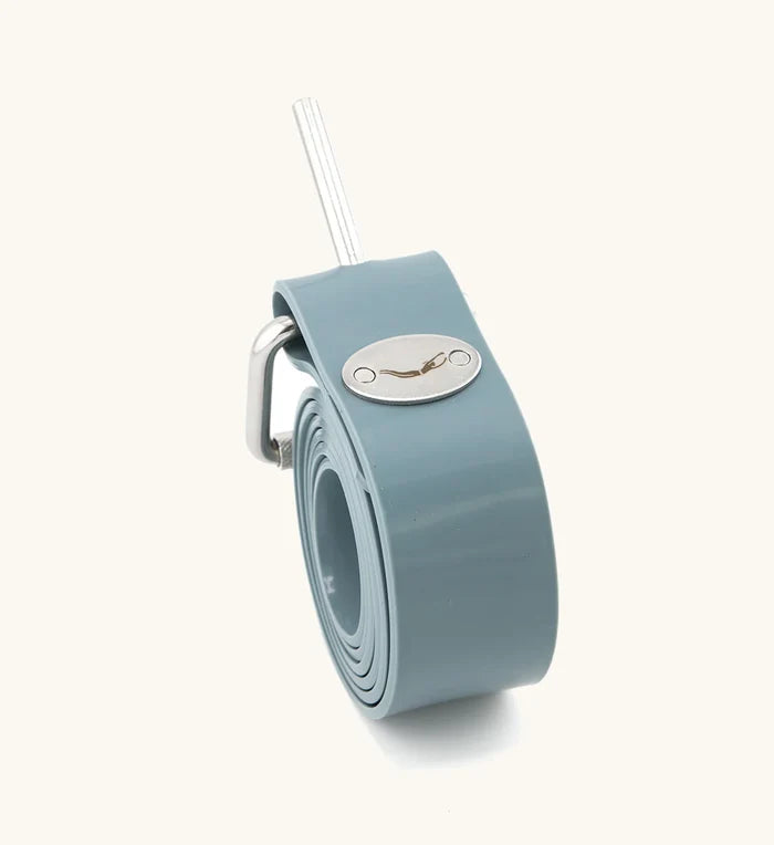 Thunderstorm rubber weight belt in blue-grey rolled up and standing upright, featuring a stainless steel pin buckle and oval Waihana brand logo plate.