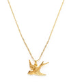 Close-up of a gold necklace with small gold charm in the shape of a bird