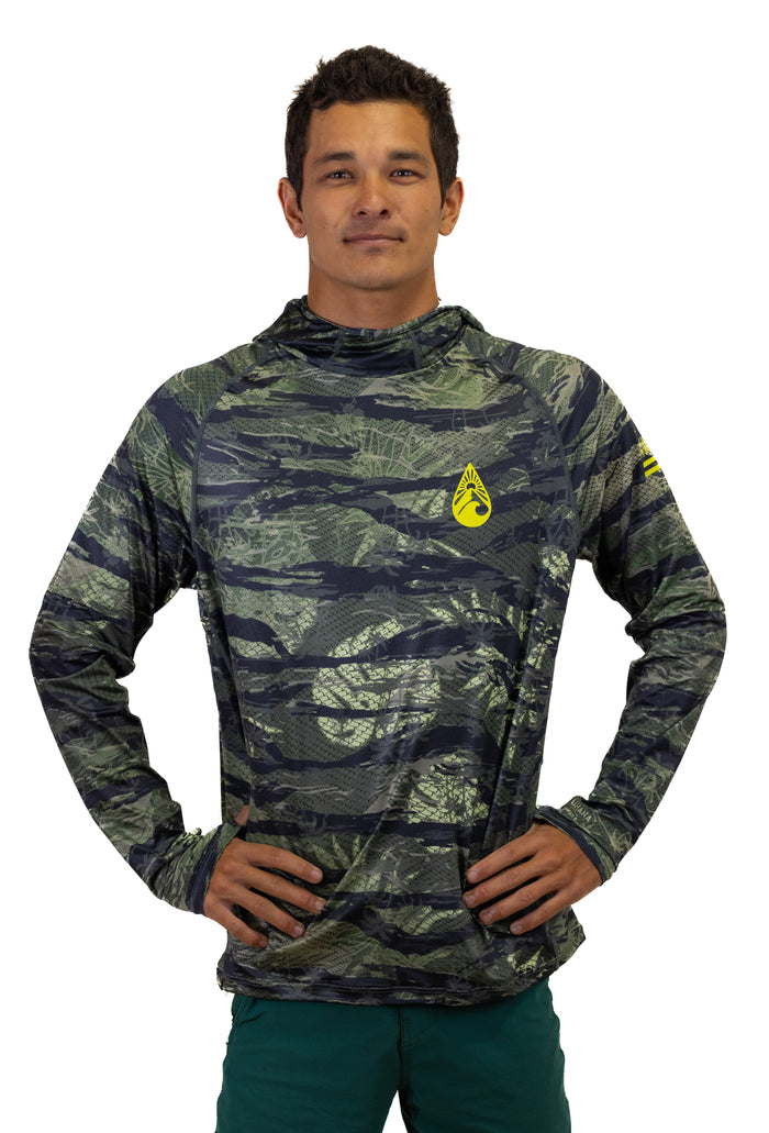 Male model wearing the Waihana Tropicam Sun Shirt in a green and navy camouflage pattern with a built-in hood and yellow Waihana logo, shown from the front against a white studio background.