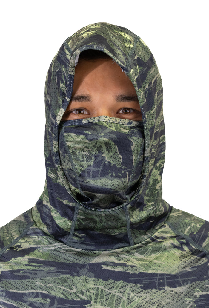 Male model wearing a Waihana Tropicam Sun Shirt with the full hood pulled up and integrated face mask covering the nose and mouth, showing the green camouflage pattern up close.