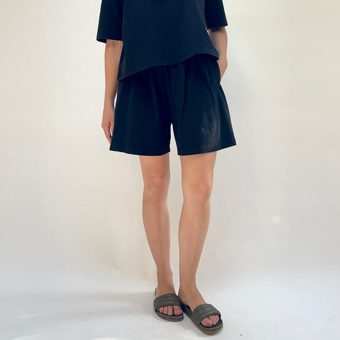 Person wearing black blue shorts and a matching top on a white background