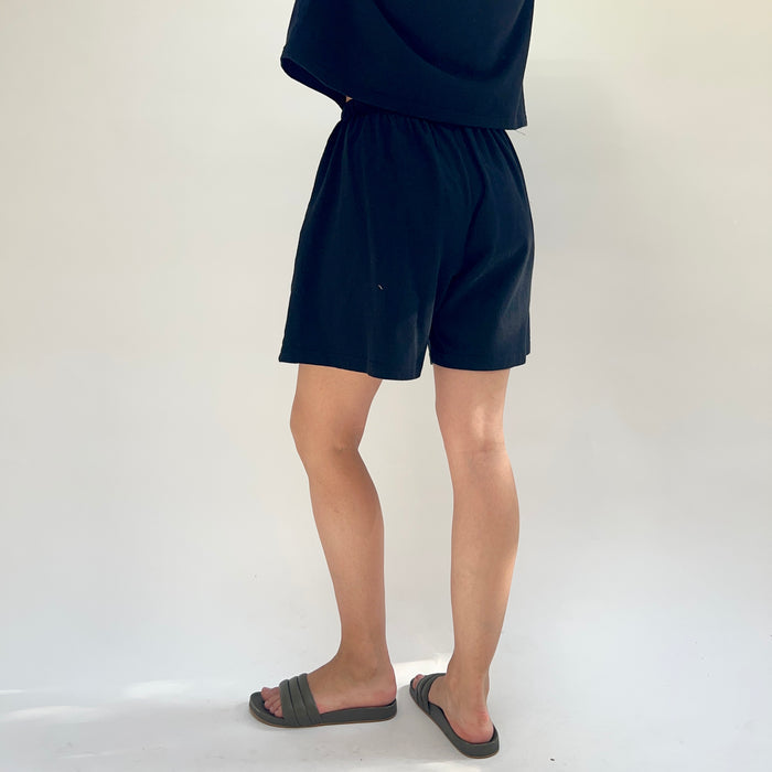 Person wearing black shorts on a white background, viewed from the back