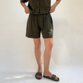 Person wearing a green outfit with shorts on a white background