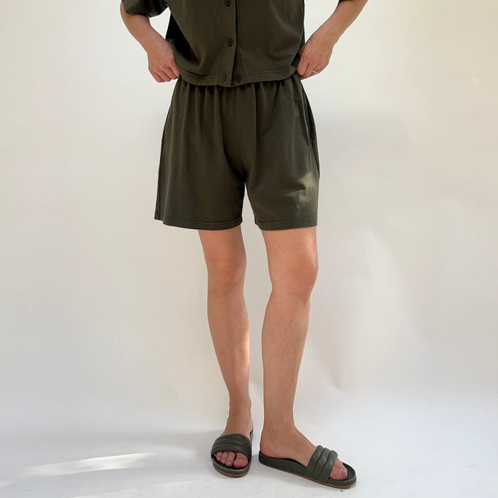 Person wearing a green outfit with shorts on a white background