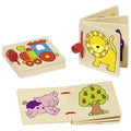 Three Goki Wooden First Stories Board Books on a white background: the Locomotive book closed showing a colorful train, the Friendly Lion book open showing a yellow lion on one page, and the Farm book open showing a pink pig and an apple tree, all with red binding rings